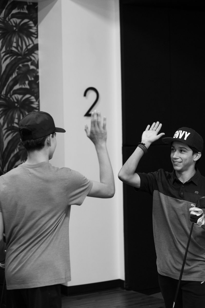 Junior golfers high-fiving after a round at Golf Envy